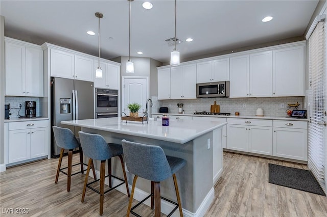 379 Mano Destra Ln, Henderson, NV 89011 - kitchen featuring stainless steel appliances, backsplash, light wood finished floors, a breakfast bar, and recessed lighting