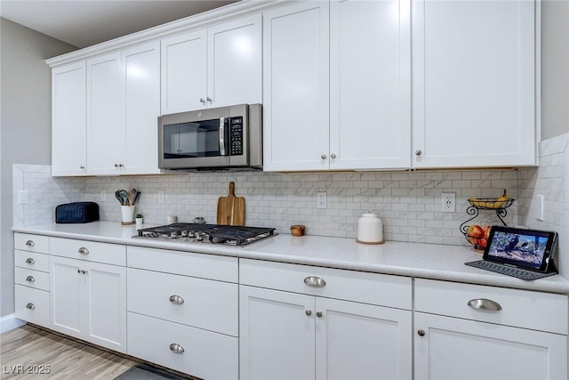 379 Mano Destra Ln, Henderson, NV 89011 - kitchen with stainless steel appliances, light countertops, white cabinets, and decorative backsplash