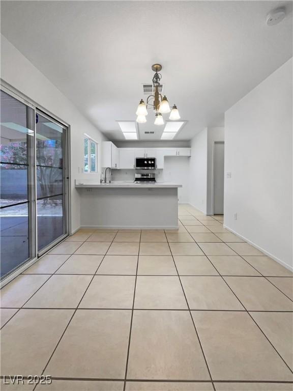 2125 Stone Well Rd, North Las Vegas, NV 89031 - kitchen with a peninsula, appliances with stainless steel finishes, white cabinets, light tile patterned floors, and light countertops