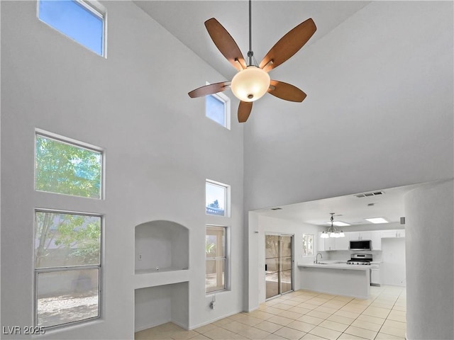 2125 Stone Well Rd, North Las Vegas, NV 89031 - unfurnished living room featuring a high ceiling, light tile patterned flooring, ceiling fan, and plenty of natural light