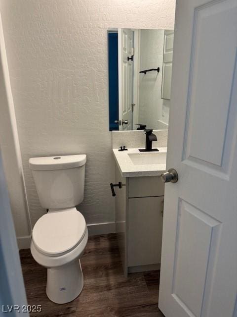1121 Sixshooter Ave, Pahrump, NV 89048 - bathroom with wood finished floors, vanity, toilet, a textured wall, and baseboards