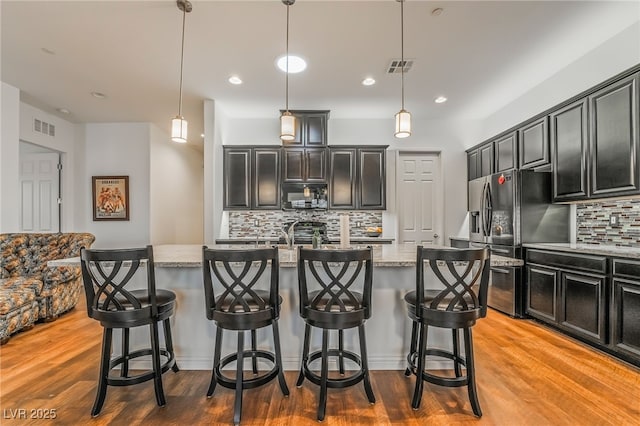 715 Orange Plume Walk, Henderson, NV 89011 - kitchen with refrigerator with ice dispenser, black microwave, tasteful backsplash, light stone counters, and an island with sink
