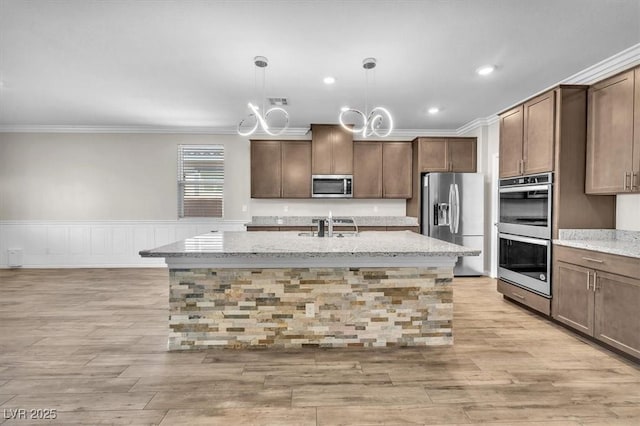 4510 Rubious Ave, North Las Vegas, NV 89084 - kitchen featuring appliances with stainless steel finishes, ornamental molding, a sink, light stone counters, and an island with sink