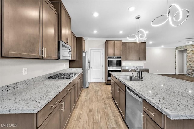 4510 Rubious Ave, North Las Vegas, NV 89084 - kitchen with appliances with stainless steel finishes, a sink, crown molding, light wood-style flooring, and an island with sink