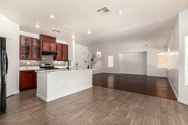 9173 Weeping Hollow Ave, Las Vegas, NV 89178 - kitchen featuring stainless steel stove, under cabinet range hood, open floor plan, wood finished floors, and tasteful backsplash