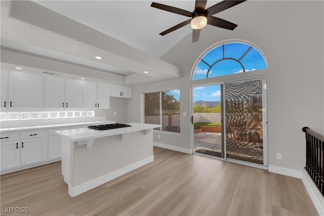 1611 Buffalo Trail Dr, Henderson, NV 89014 - kitchen with white cabinetry, a kitchen island, light countertops, light wood-style floors, and black gas cooktop