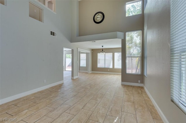 1917 Badger Canyon Ave, North Las Vegas, NV 89031 - unfurnished living room featuring a high ceiling, a chandelier, healthy amount of natural light, and baseboards