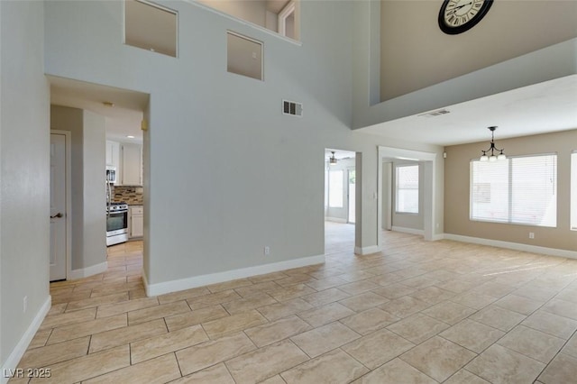 1917 Badger Canyon Ave, North Las Vegas, NV 89031 - unfurnished living room with a chandelier, baseboards, a towering ceiling, and light tile patterned floors
