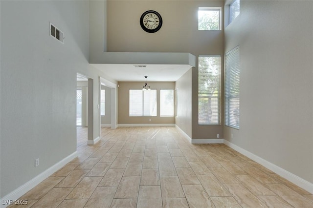 1917 Badger Canyon Ave, North Las Vegas, NV 89031 - unfurnished living room featuring a towering ceiling, a chandelier, and baseboards