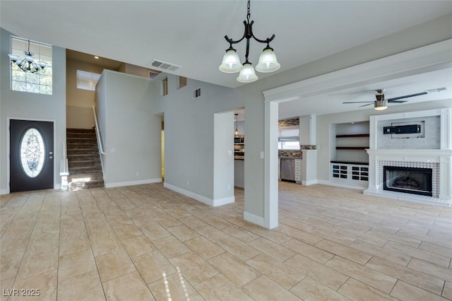 1917 Badger Canyon Ave, North Las Vegas, NV 89031 - unfurnished living room featuring a chandelier, stairs, a fireplace with raised hearth, ceiling fan, and healthy amount of natural light