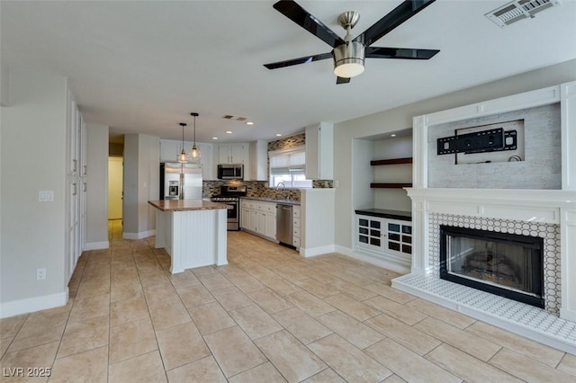 1917 Badger Canyon Ave, North Las Vegas, NV 89031 - kitchen featuring appliances with stainless steel finishes, ceiling fan, white cabinetry, a tiled fireplace, and baseboards