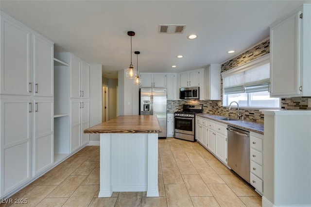 1917 Badger Canyon Ave, North Las Vegas, NV 89031 - kitchen with appliances with stainless steel finishes, open shelves, a sink, white cabinets, and tasteful backsplash