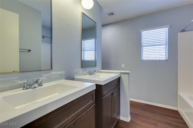 1917 Badger Canyon Ave, North Las Vegas, NV 89031 - bathroom featuring two vanities, wood finished floors, shower / washtub combination, baseboards, and tasteful backsplash