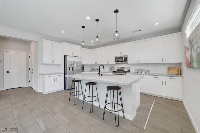 1321 Hudson Creek Pl, North Las Vegas, NV 89084 - kitchen featuring stainless steel appliances, decorative backsplash, a kitchen breakfast bar, a sink, and light countertops