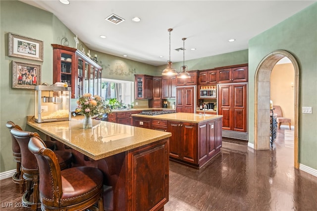 2346 Villandry Ct, Henderson, NV 89074 - kitchen featuring stainless steel appliances, a peninsula, arched walkways, glass insert cabinets, and baseboards
