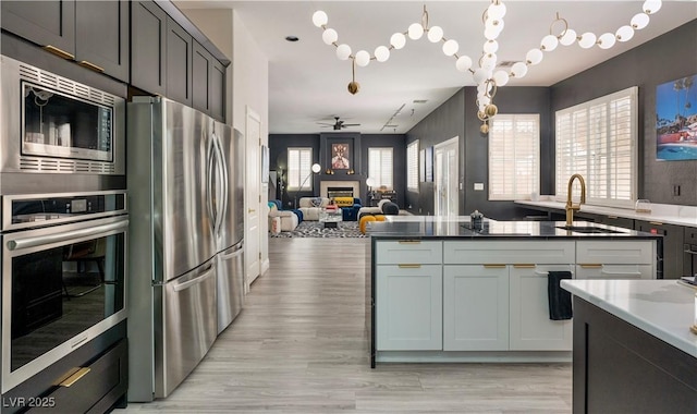464 Beardsley Cir, Henderson, NV 89052 - kitchen with appliances with stainless steel finishes, a sink, a fireplace, open floor plan, and light wood-style floors