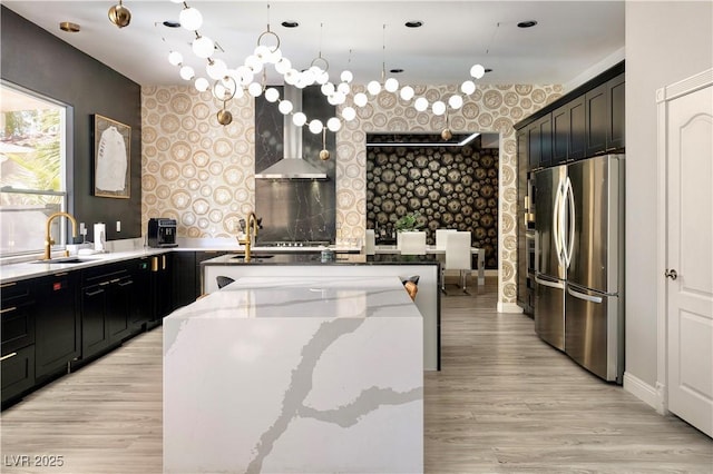 464 Beardsley Cir, Henderson, NV 89052 - kitchen with freestanding refrigerator, wallpapered walls, a sink, an accent wall, and light stone countertops