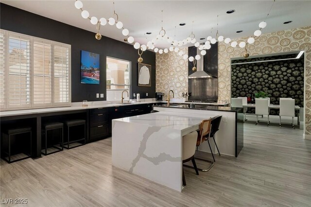464 Beardsley Cir, Henderson, NV 89052 - kitchen featuring wallpapered walls, a sink, wall chimney range hood, an accent wall, and a center island