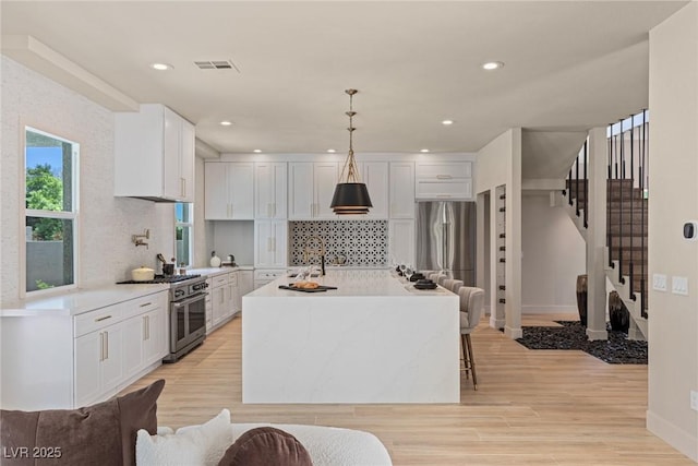 11550 Lampeter Ct, Las Vegas, NV 89138 - kitchen featuring appliances with stainless steel finishes, tasteful backsplash, a center island with sink, white cabinetry, and recessed lighting
