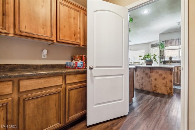 574 Desert Tortoise Way, Mesquite, NV 89027 - kitchen with brown cabinets, dark wood finished floors, dark countertops, and recessed lighting