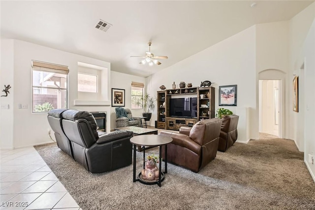 7515 Splashing Rock Dr, Las Vegas, NV 89131 - living area featuring ceiling fan, a glass covered fireplace, high vaulted ceiling, light tile patterned floors, and baseboards