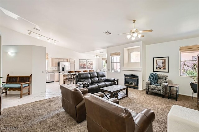 7515 Splashing Rock Dr, Las Vegas, NV 89131 - living area with a ceiling fan, vaulted ceiling, plenty of natural light, a glass covered fireplace, and light tile patterned flooring
