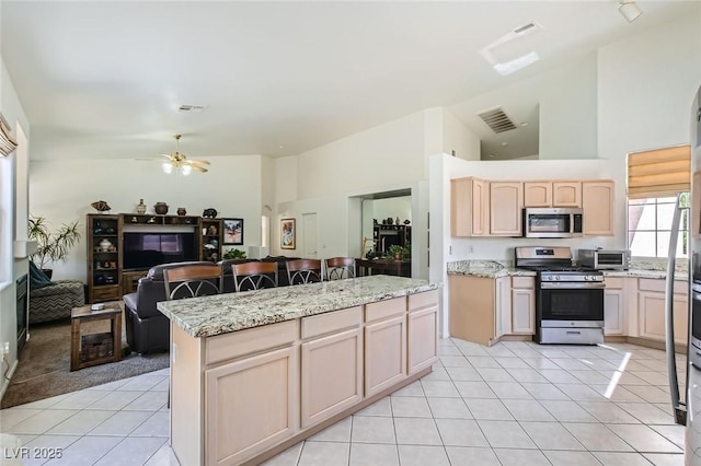 7515 Splashing Rock Dr, Las Vegas, NV 89131 - kitchen with stainless steel appliances, light tile patterned floors, open floor plan, a ceiling fan, and a center island