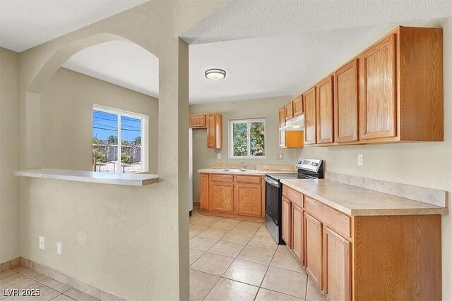 2257 Colebrook St, Las Vegas, NV 89115 - kitchen featuring range with electric stovetop, light tile patterned flooring, under cabinet range hood, and healthy amount of natural light