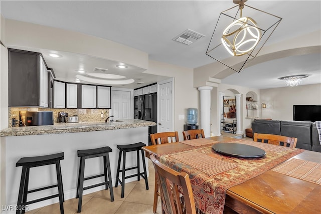 7197 Sixshooter Dr, Las Vegas, NV 89119 - dining room featuring decorative columns, light tile patterned floors, arched walkways, and a chandelier