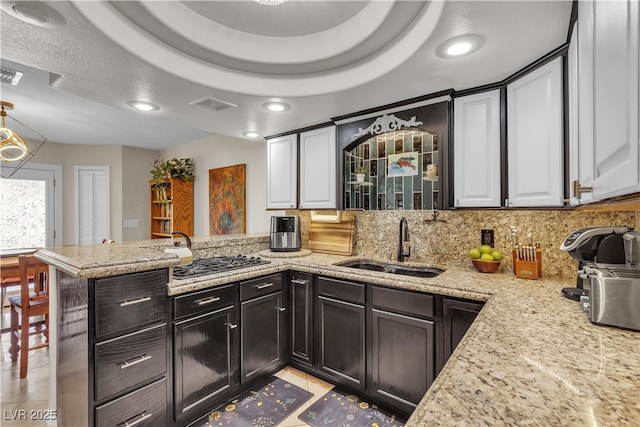 7197 Sixshooter Dr, Las Vegas, NV 89119 - kitchen featuring a sink, a peninsula, backsplash, light tile patterned flooring, and gas stovetop