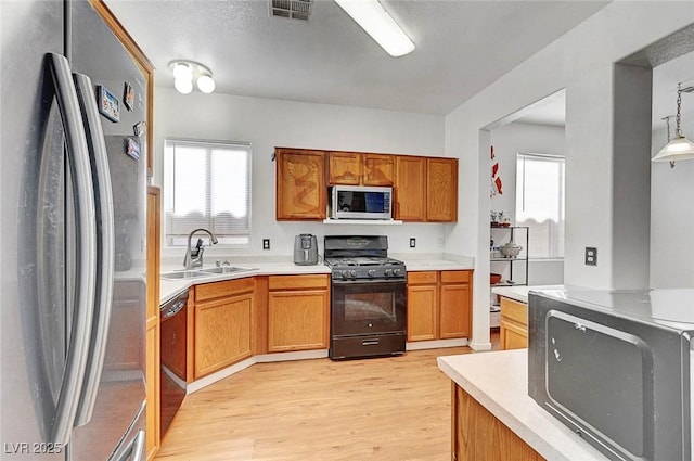 1025 Clover Tip Ct, Las Vegas, NV 89123 - kitchen with black appliances, a sink, light wood-style floors, light countertops, and brown cabinets