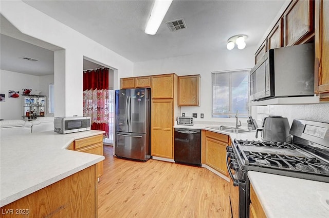 1025 Clover Tip Ct, Las Vegas, NV 89123 - kitchen with black appliances, a sink, light wood finished floors, light countertops, and brown cabinets
