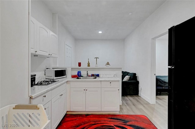 1025 Clover Tip Ct, Las Vegas, NV 89123 - kitchen with white microwave, light wood finished floors, white cabinets, a sink, and light countertops