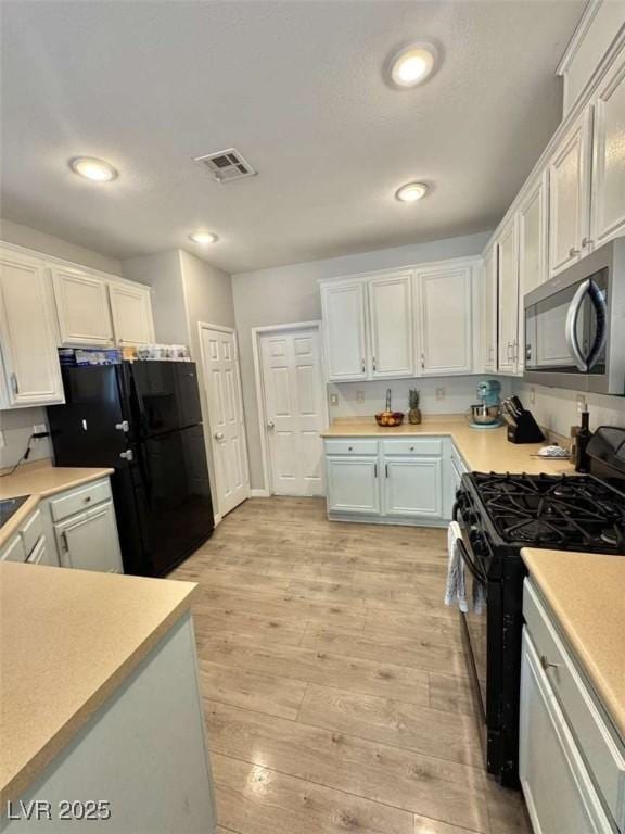 1355 Grass Creek Ave Unit 1, Henderson, NV 89012 - kitchen featuring black appliances, light countertops, light wood-type flooring, white cabinetry, and recessed lighting