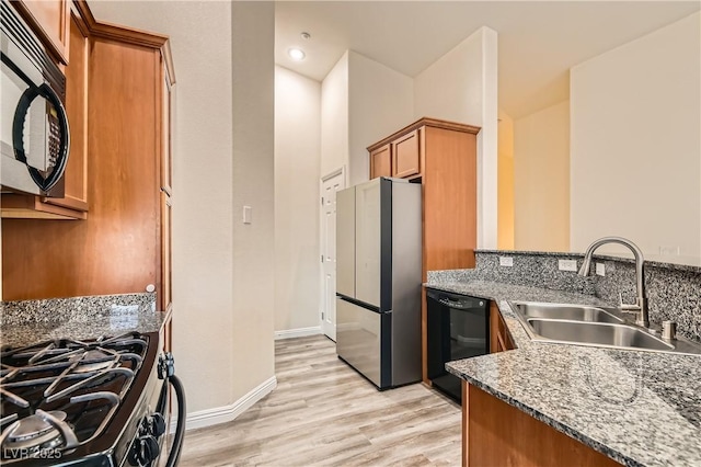 10147 Aspen Rose St Unit 101, Las Vegas, NV 89183 - kitchen featuring black appliances, a sink, brown cabinetry, light wood-type flooring, and stone countertops