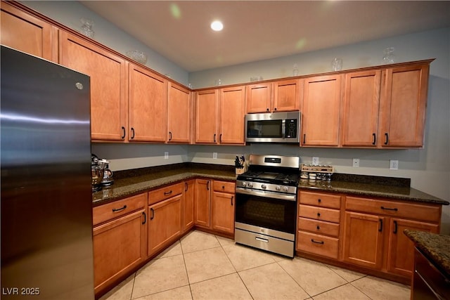 7727 Widewing Dr, North Las Vegas, NV 89084 - kitchen with stainless steel appliances, light tile patterned floors, brown cabinets, dark stone countertops, and recessed lighting