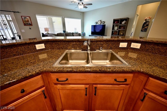 7727 Widewing Dr, North Las Vegas, NV 89084 - kitchen with a sink, ceiling fan, brown cabinets, open floor plan, and dark stone counters