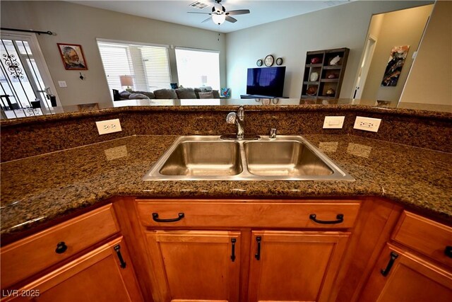 7727 Widewing Dr, North Las Vegas, NV 89084 - kitchen featuring a sink, a ceiling fan, brown cabinets, open floor plan, and dark stone countertops
