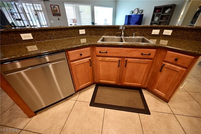7727 Widewing Dr, North Las Vegas, NV 89084 - kitchen with stainless steel dishwasher, a sink, brown cabinets, dark stone countertops, and light tile patterned flooring