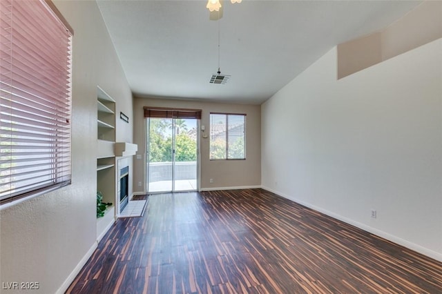 3336 Hidden Ridge St, Las Vegas, NV 89129 - unfurnished living room featuring wood finished floors, baseboards, built in shelves, a fireplace, and lofted ceiling