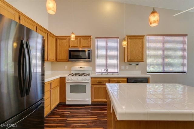 3336 Hidden Ridge St, Las Vegas, NV 89129 - kitchen with freestanding refrigerator, gas range gas stove, stainless steel microwave, dark wood-style floors, and tile counters