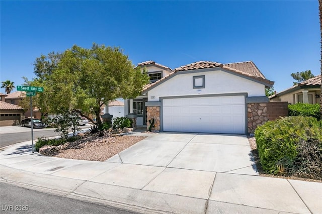 3336 Hidden Ridge St, Las Vegas, NV 89129 - mediterranean / spanish home with stone siding, a tiled roof, an attached garage, concrete driveway, and stucco siding