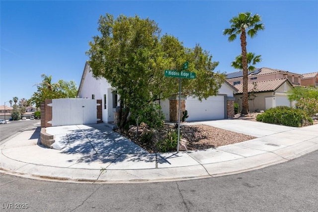 3336 Hidden Ridge St, Las Vegas, NV 89129 - obstructed view of property with driveway, a gate, stucco siding, and stone siding