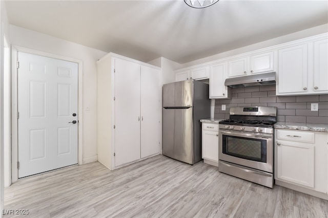 5280 Shreve Ave, Las Vegas, NV 89156 - kitchen with stainless steel appliances, under cabinet range hood, light wood finished floors, white cabinets, and decorative backsplash