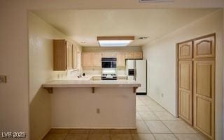 2851 S Valley View Blvd Unit 1199, Las Vegas, NV 89102 - kitchen with fridge with ice dispenser, a peninsula, light countertops, light tile patterned floors, and a breakfast bar