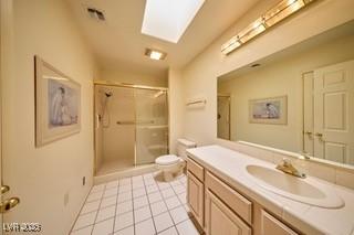 2851 S Valley View Blvd Unit 1199, Las Vegas, NV 89102 - full bathroom featuring toilet, vanity, tile patterned floors, a stall shower, and a skylight