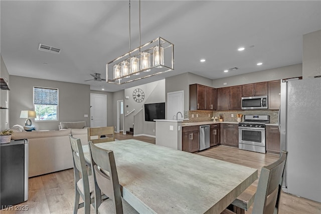 3132 Cartanda Ave, Henderson, NV 89044 - kitchen with stainless steel appliances, open floor plan, light countertops, light wood finished floors, and decorative backsplash
