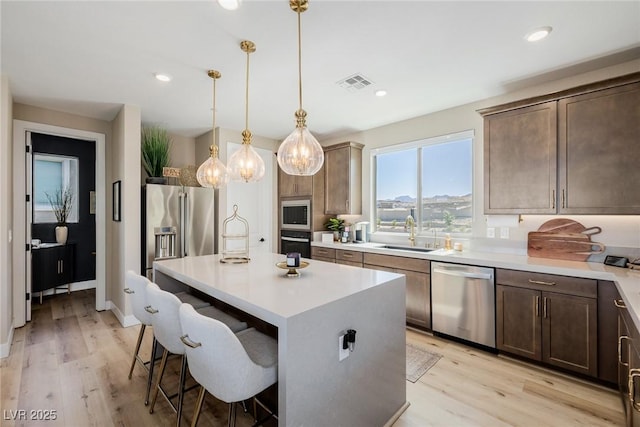 2151 Noble Perch St, Las Vegas, NV 89138 - kitchen with appliances with stainless steel finishes, light wood finished floors, a kitchen breakfast bar, a center island, and light countertops