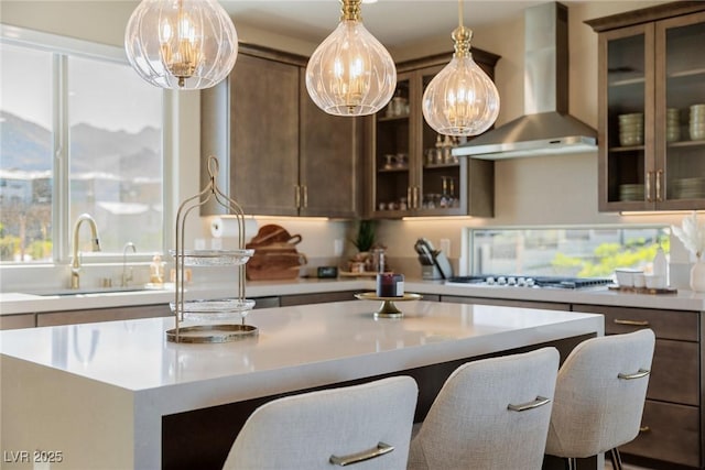 2151 Noble Perch St, Las Vegas, NV 89138 - kitchen with wall chimney exhaust hood, gas stovetop, light countertops, a center island, and hanging light fixtures