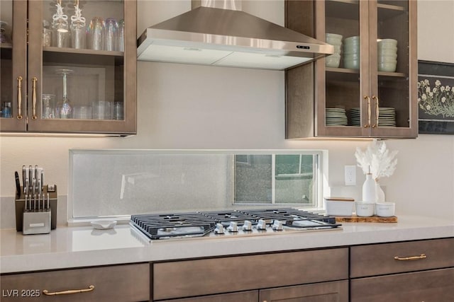 2151 Noble Perch St, Las Vegas, NV 89138 - kitchen with wall chimney exhaust hood, light countertops, glass insert cabinets, and stainless steel gas stovetop